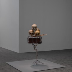 Anri Sala, "Still life in the Doldrums (d’après Cézanne)", four hand-painted human skulls, altered snare drum, carved American Maple drumsticks, altered snare stand, loudspeaker parts, and mono sound, 110 x 56 x 41 cm, 7:18 min, 2015. Maja Hoffmann / LUMA Foundation Photo: Maris Hutchinson / EPW Studio